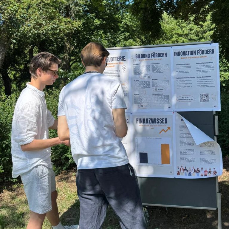 Edunovo bringt Bildung in allen Formen Zwei Personen betrachten ein Informationsplakat im Freien.